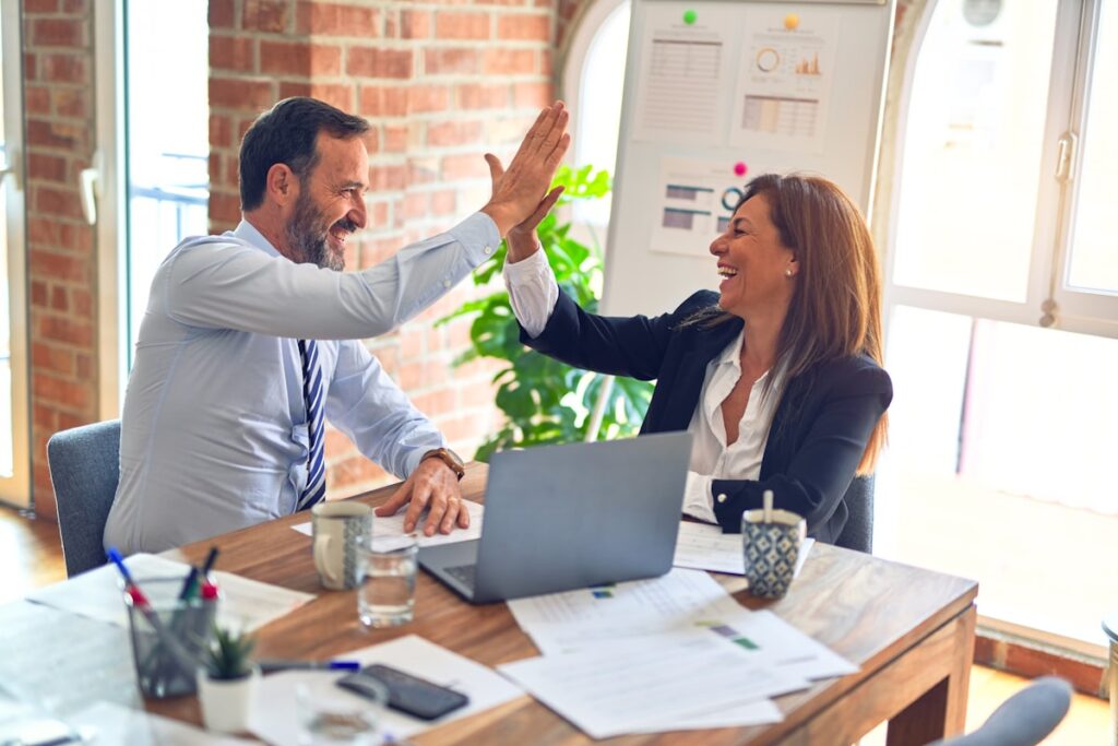Business owner and marketer high-fiving across a desk after reviewing results
