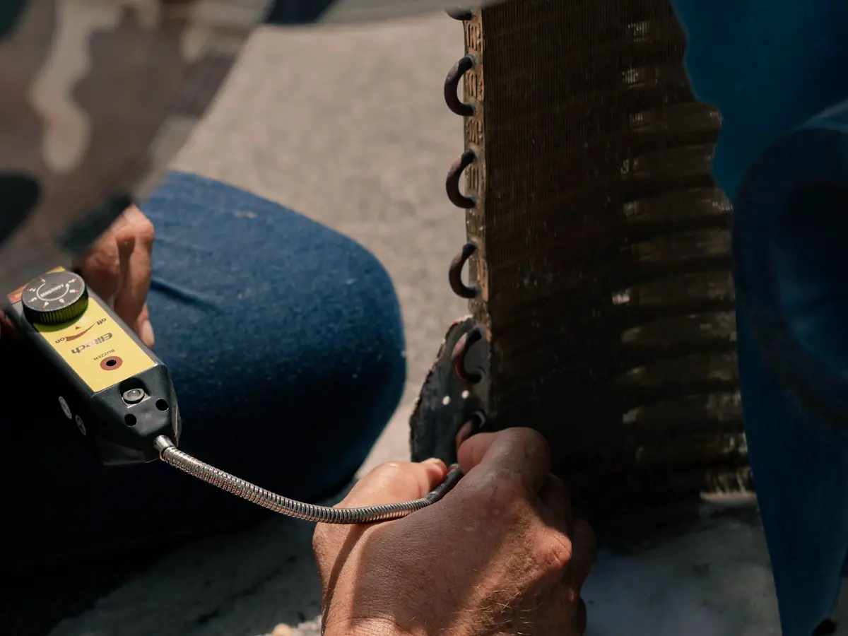 Technician using a pressure gauge while servicing an air conditioning system
