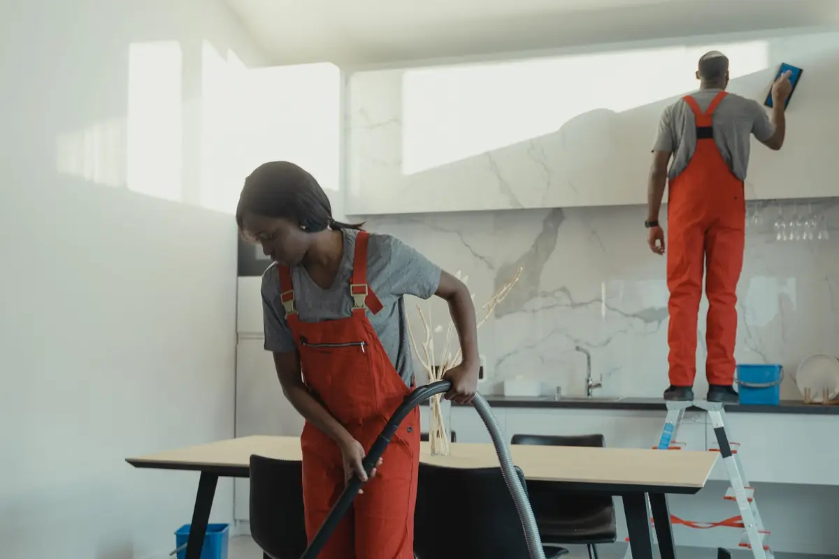 Two cleaning professionals working in a bright modern kitchen