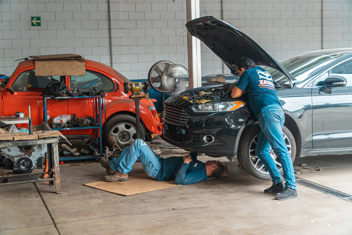 Mechanics working on two cars in an auto repair shop