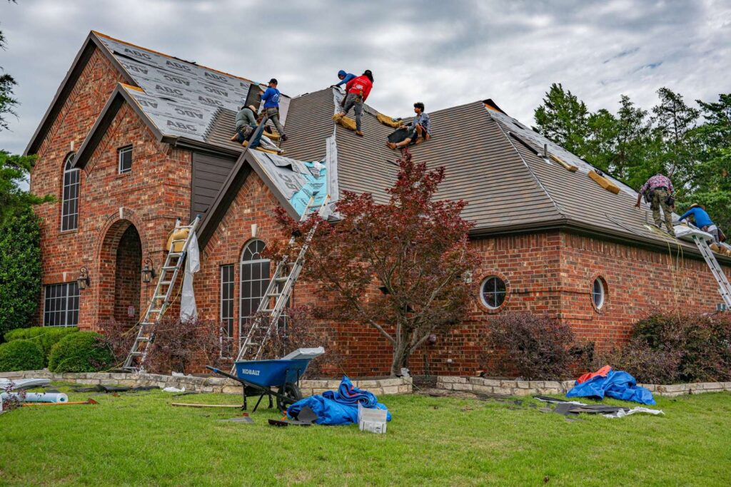 Roofers working on the roof of a brick home