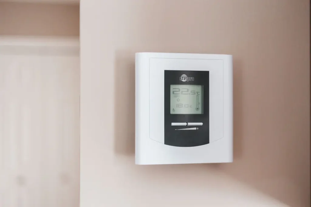 Digital thermostat mounted on a light-colored wall