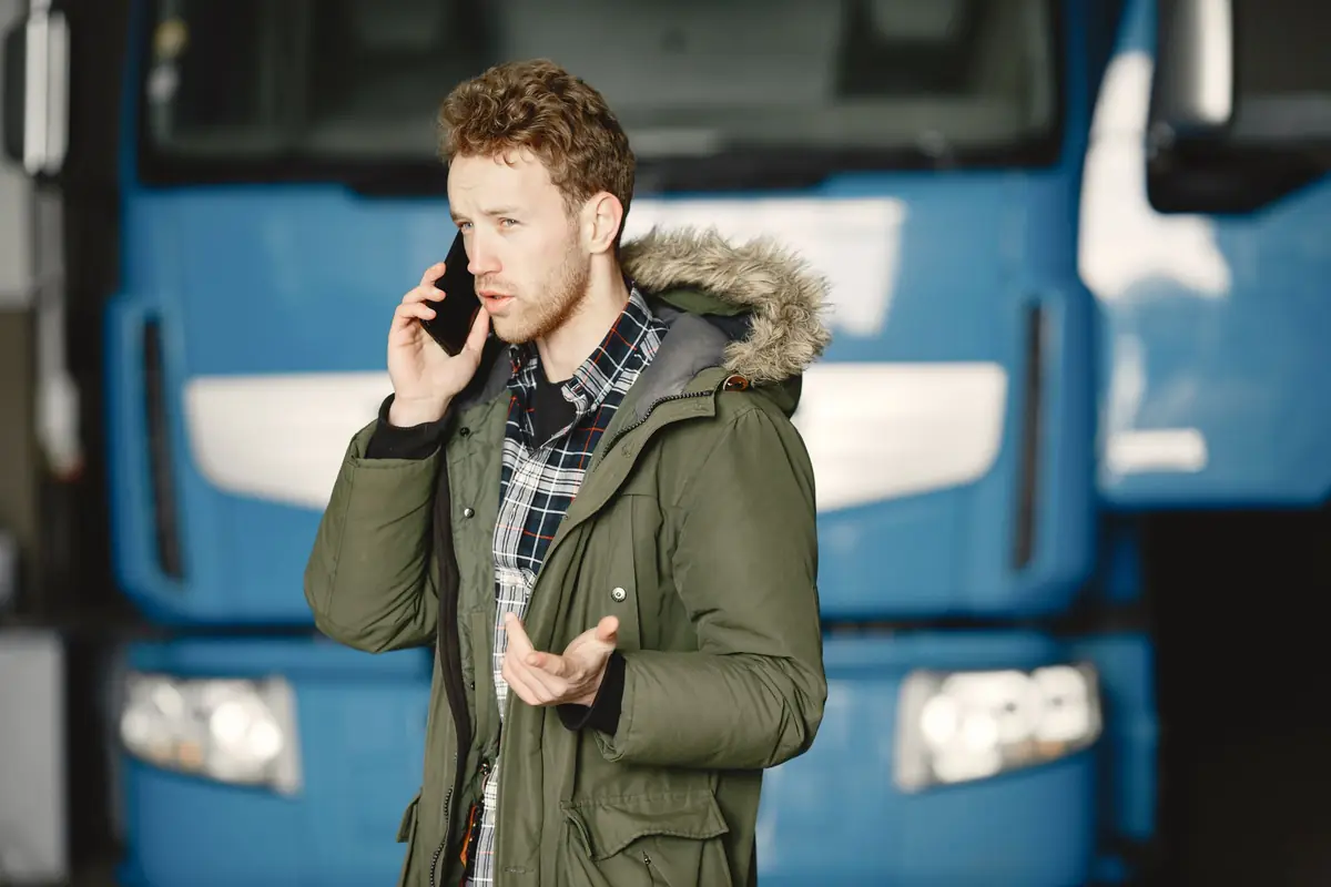 Tradesman in a work jacket talking on his phone beside a work truck