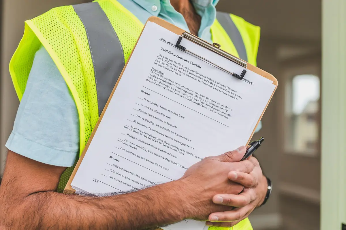 Worker in a yellow safety vest holding a pen and a printed checklist on a clipboard