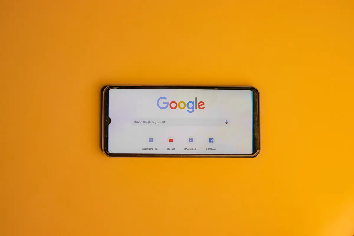 Smartphone showing the Google search page on a bright yellow background
