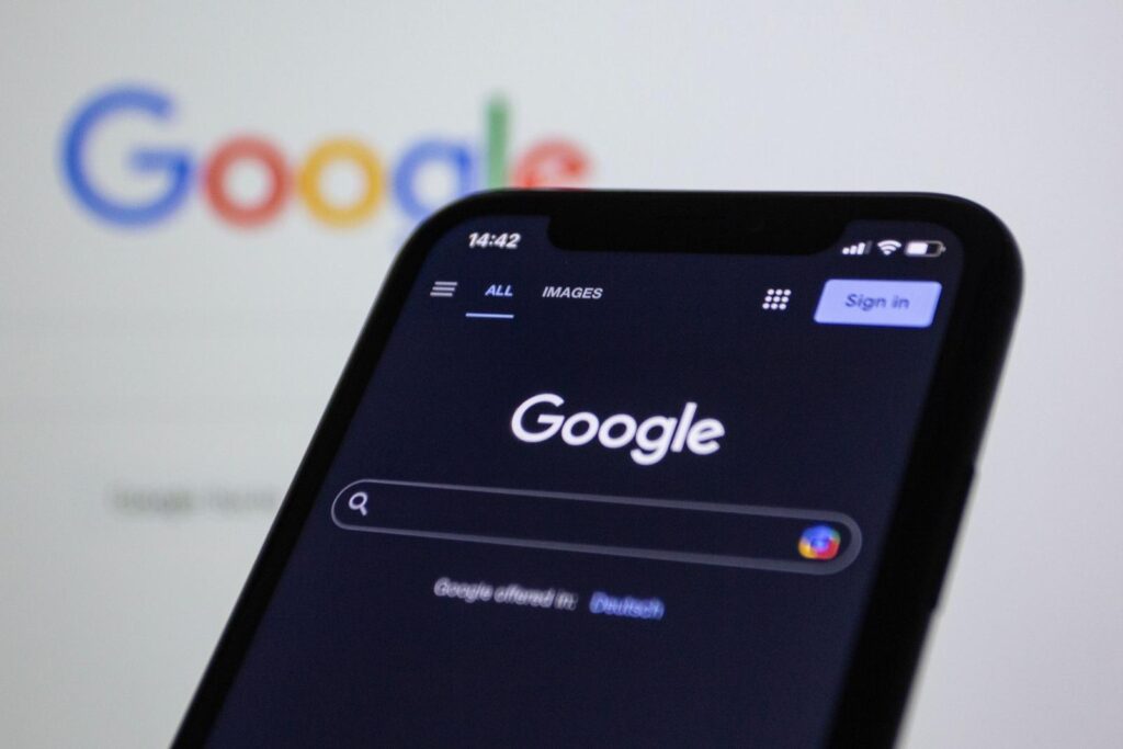 Smartphone showing the Google search page in front of a screen displaying the Google logo