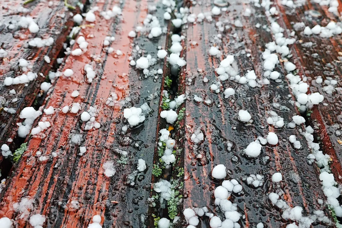 Hailstones scattered across a wooden deck after a storm