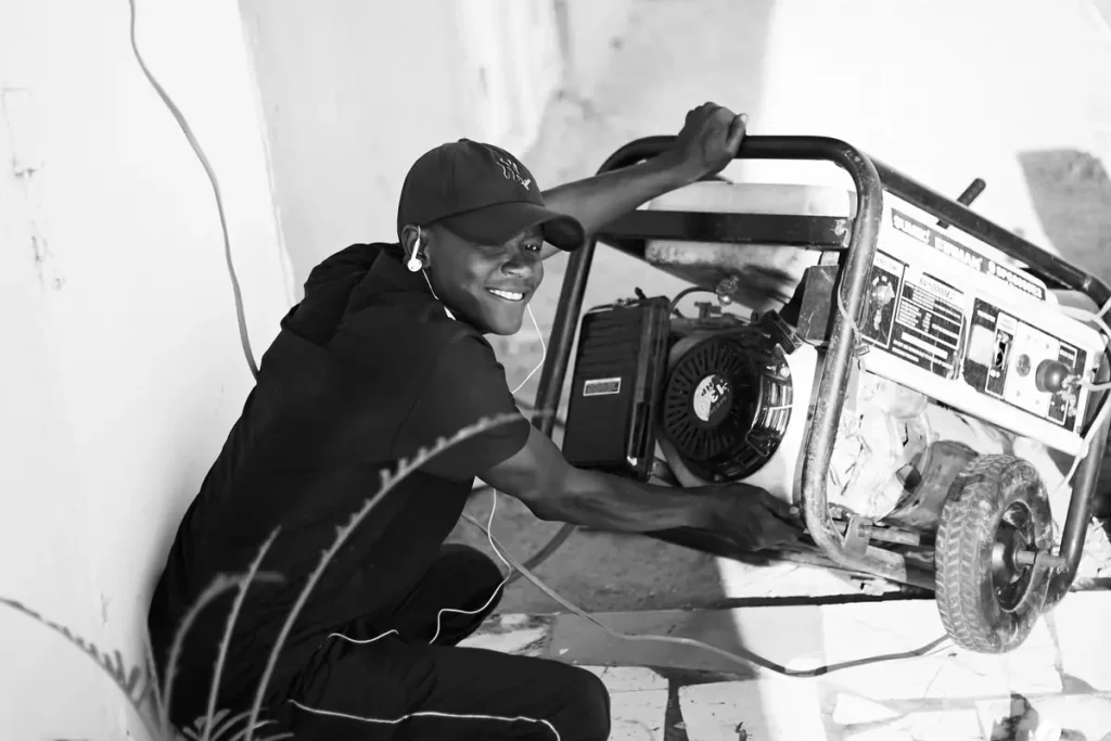 Black-and-white photo of a man starting a portable generator outdoors