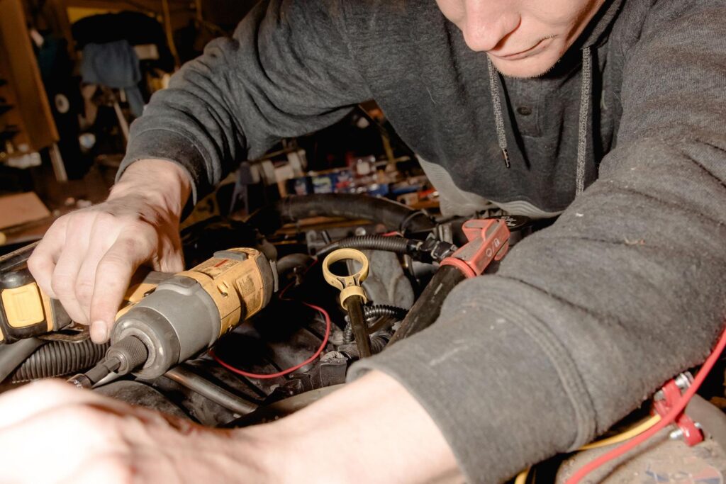 Mechanic using a power tool on a car engine in a repair shop