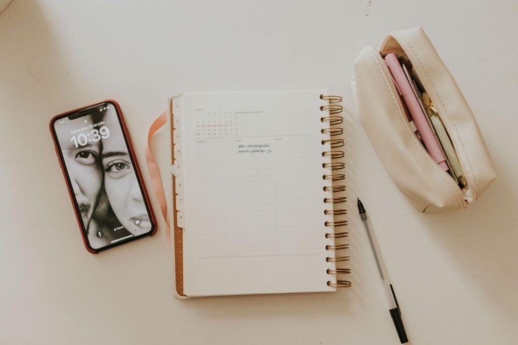 Open planner, pen, and smartphone laid out on a desk for monthly planning