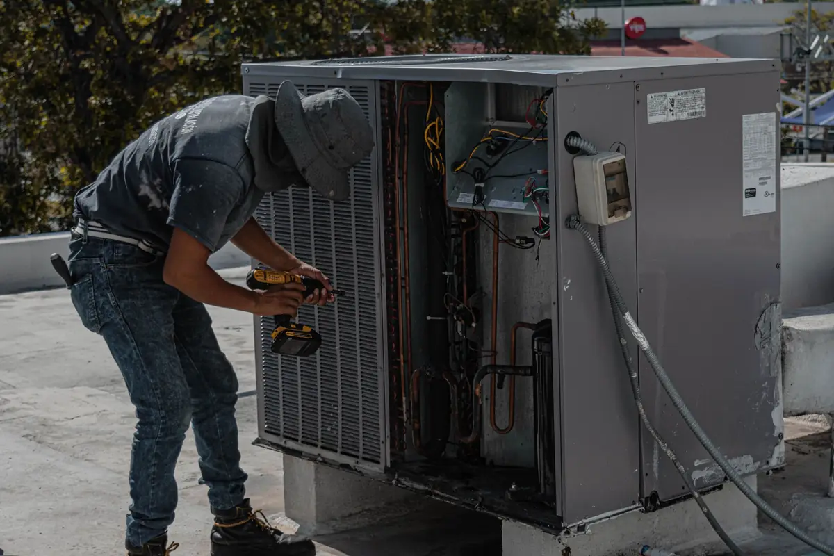 HVAC technician repairing an outdoor air conditioning unit on a rooftop